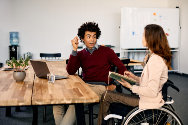 Black businessman and his female colleague in wheelchair talking while working in the office. Registered NDIS Provider Melbourne