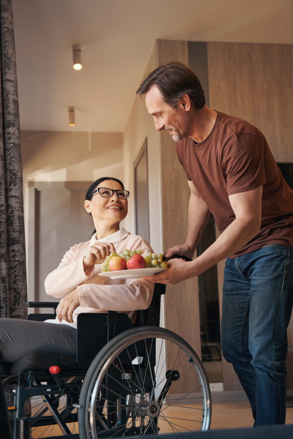 Smiling man bringing fruit for wife with paraleria Registered NDIS Provider Melbourne